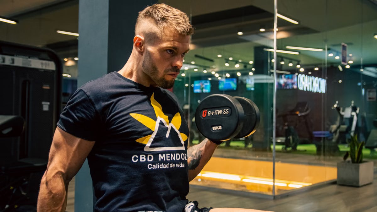 Male athlete focused on weightlifting exercise at the gym with dumbbells, showcasing strength and fitness goals.